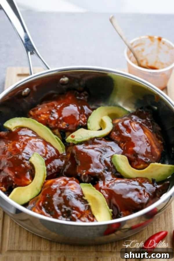 Tangy Barbecue Buffalo Chicken Thighs with Creamy Avocado 4 Golden-brown Crispy Barbecue Buffalo Chicken Thighs served in a rustic pan with fresh avocado slices.