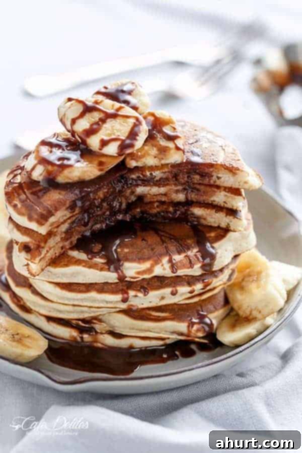 Gooey Nutella Banana Pancake Bliss 4 Nutella Stuffed Banana Pancakes stack on each other on a plate