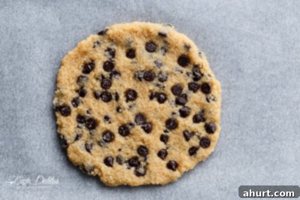 Raw dough for a single serve jumbo low carb chocolate chip cookie placed on parchment paper, ready to be baked to golden perfection.