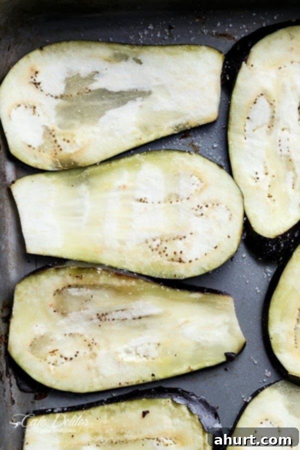 Eggplant slices on a baking tray, seasoned with olive oil and salt, ready for roasting.