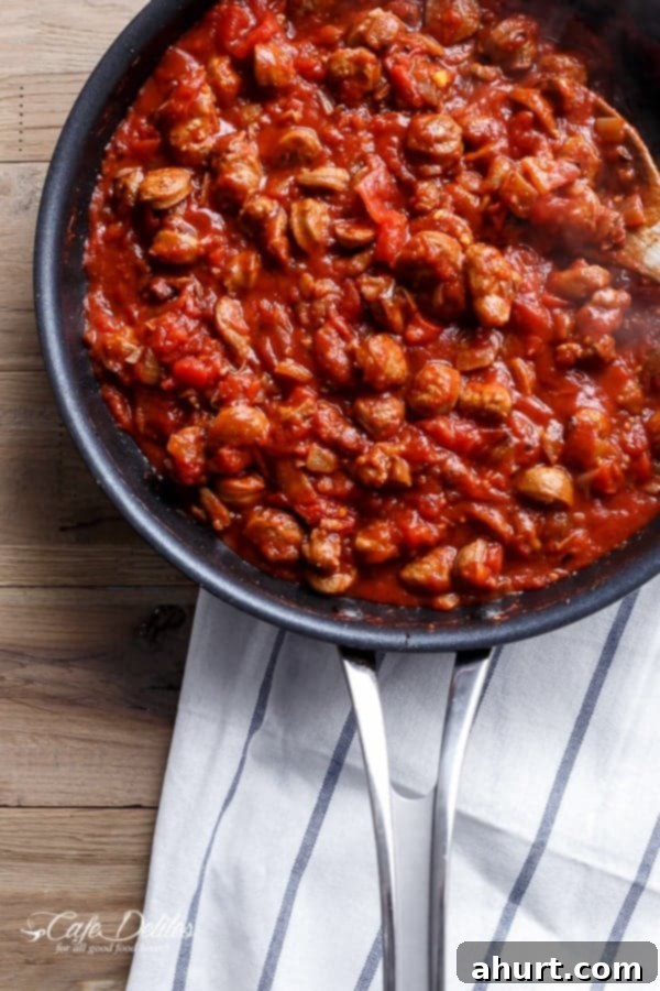 Sausage Eggplant Lasagna mixture simmering on a pan, showing a rich, red bolognese sauce with sliced sausages.