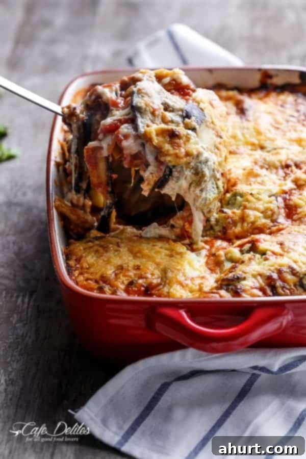 A piece of Sausage Eggplant Lasagna With Ricotta Pesto taken from the tray, showcasing the layers.
