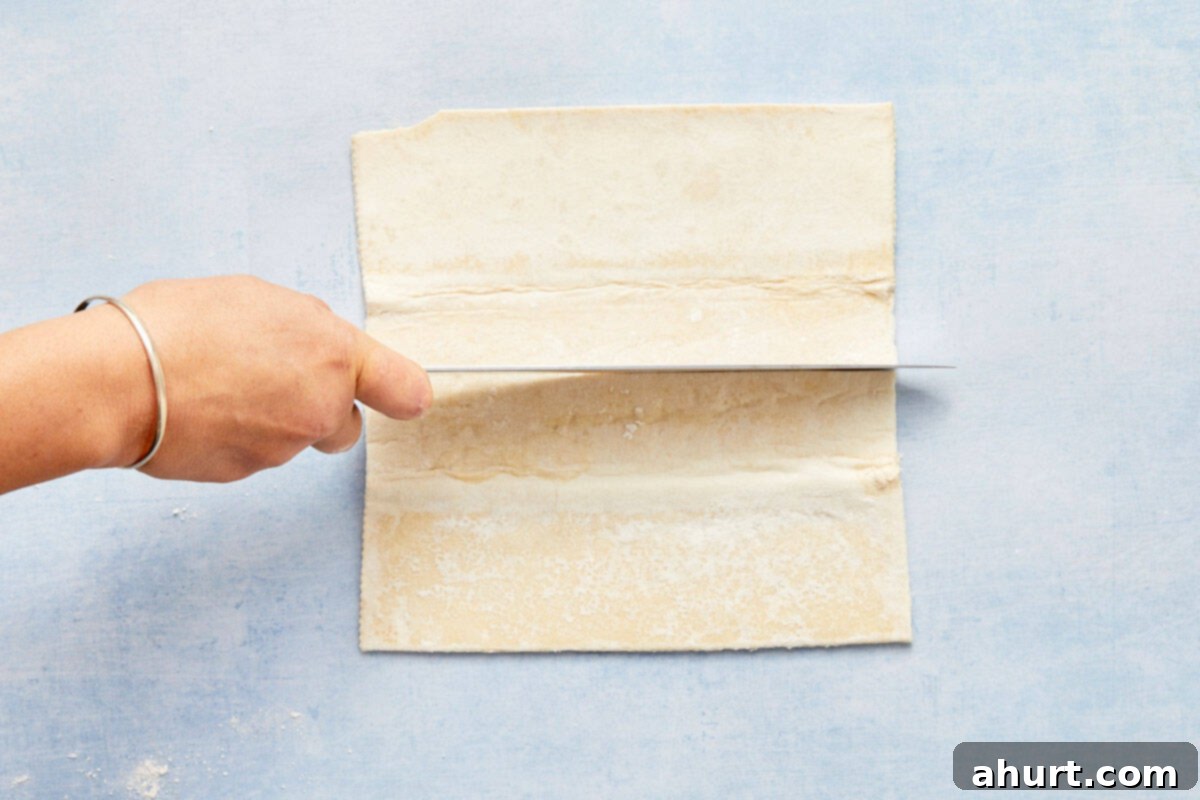 Flaky Salmon and Spinach Pockets 7 Puff pastry sheets being cut into rectangles on a light blue background.