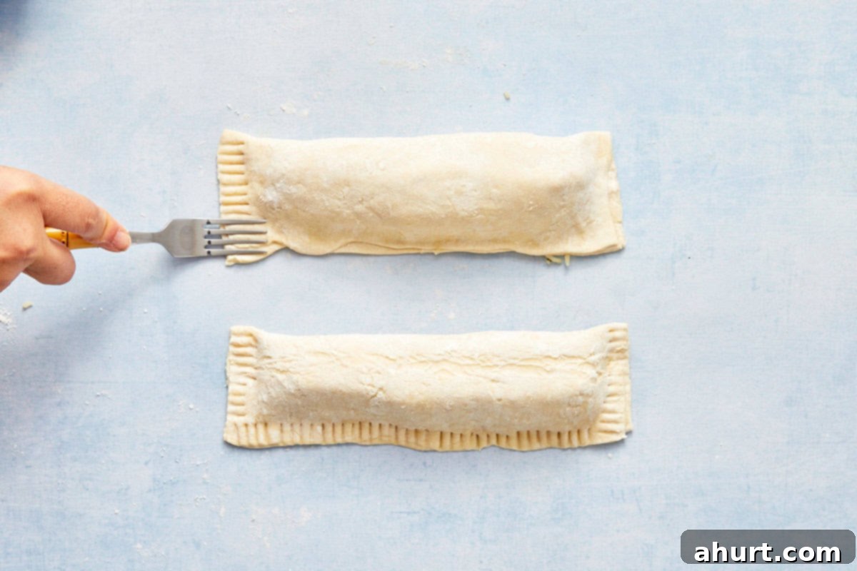 Flaky Salmon and Spinach Pockets 10 Fork pressing the edges of the puff pastry parcel to seal it.