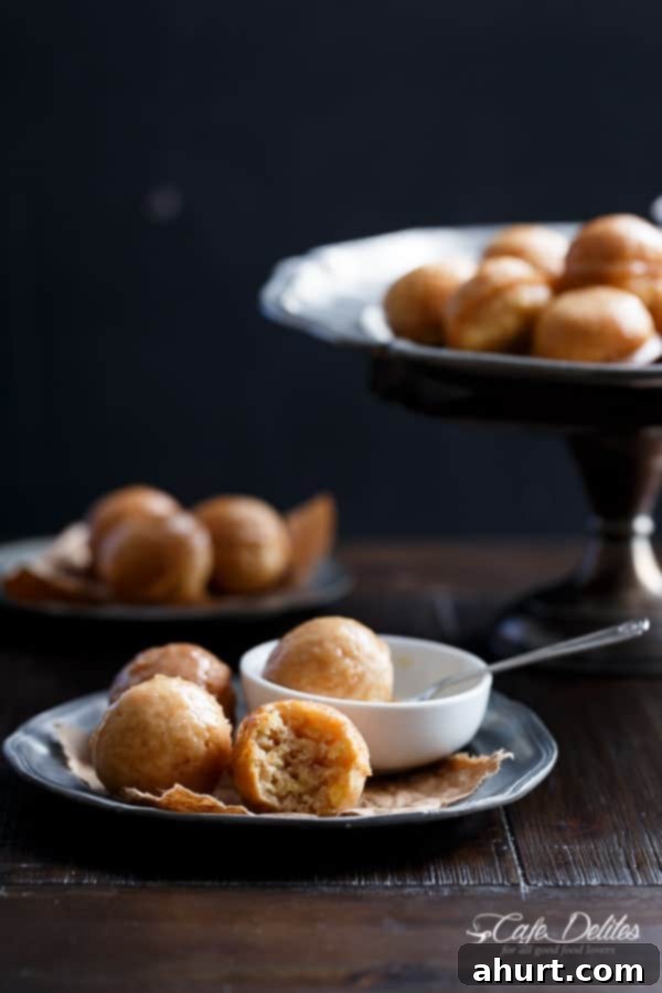 Stack of golden brown baked maple glazed apple fritter donut holes on a rustic plate