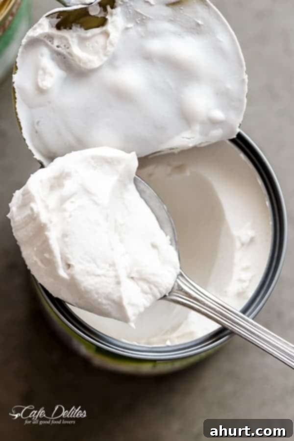 Cloud-Like Coconut Topping 3 Scooping thick coconut cream from a can with a spoon