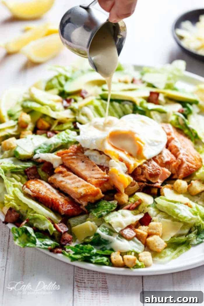 Salmon Caesar Salad with creamy avocado, crunchy croutons, shaved parmesan, a runny poached egg, and a lightened-up Caesar dressing