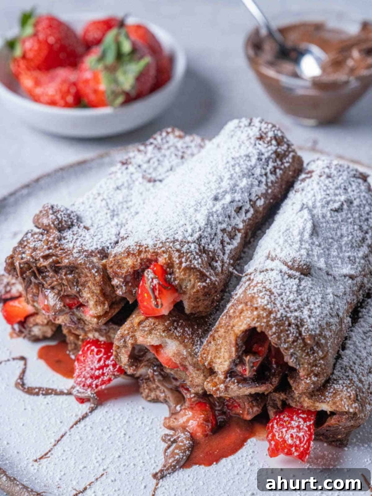 French Toast Rolls Breakfast Perfection 2 A picture of delicious French Toast Roll Ups filled with Nutella and strawberries, topped with a dusting of icing sugar, ready to be enjoyed as a delightful breakfast or brunch.