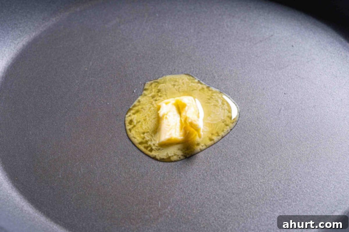 French Toast Rolls Breakfast Perfection 7 A close up image of a knob of butter melting in a skillet, preparing for the French toast rolls.