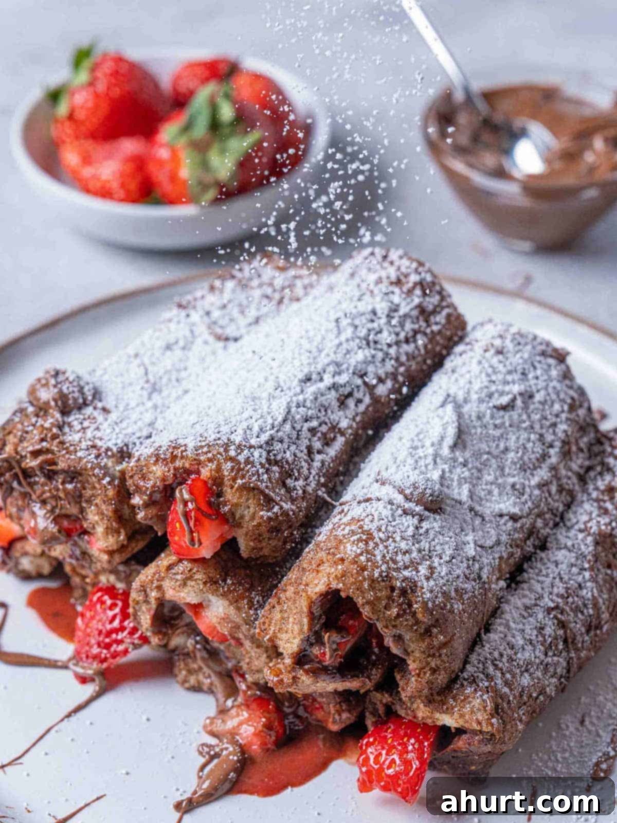 French Toast Rolls Breakfast Perfection 10 Image of the finished French toast roll-ups with icing sugar being sprinkled on top, ready to be served.
