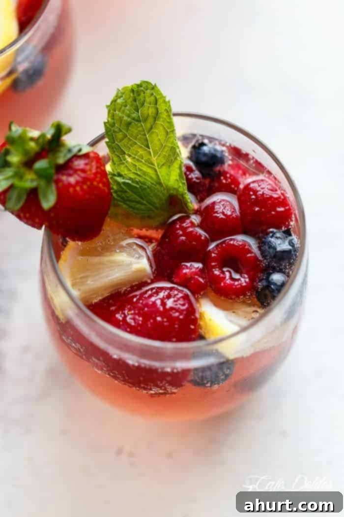 A glass of Berry Limoncello Moscato Sangria with mint leaves and berries, ready to be served.