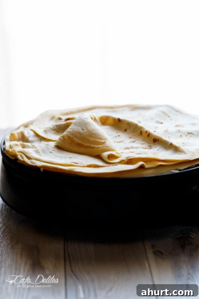 Freshly cooked Blender Eggnog Crêpes stacked and ready for filling or topping on a white plate