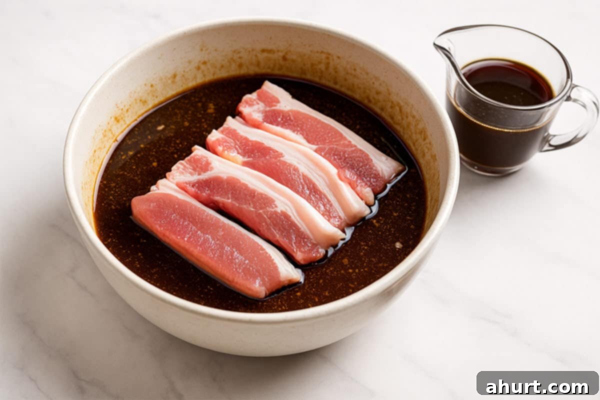 Glazed Char Siu Pork Belly 5 A slab of pork belly added to the bowl, covered in sauce. Another small jug nearby with reserved marinade.