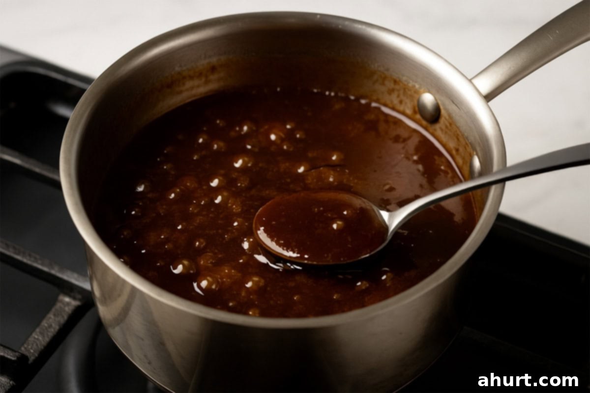 Glazed Char Siu Pork Belly 7 Simmering glaze in a stainless steel saucepan with natural bubbles and a rich, glossy texture, seen close-up from above.