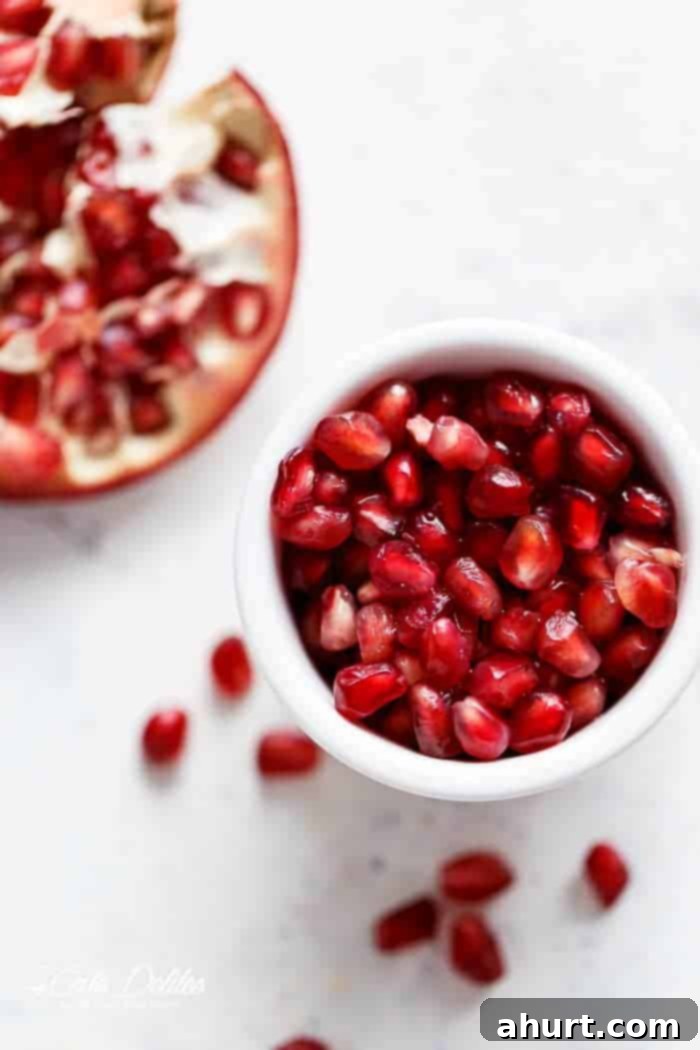 Jeweled Cobb Salad 3 Close-up of bright red pomegranate arils in a small white bowl, ready to be added to the salad.