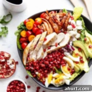 Jeweled Cobb Salad 7 Pomegranate Cobb Salad in a white bowl, close-up, showcasing its vibrant ingredients.