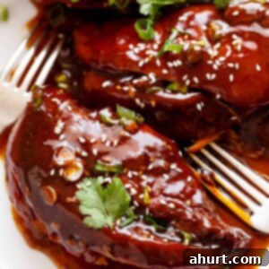 Sticky Sweet Slow Cooker Asian Chicken 5 Slow Cooker Asian Glazed Chicken, shredded and ready to eat, served with a fork.