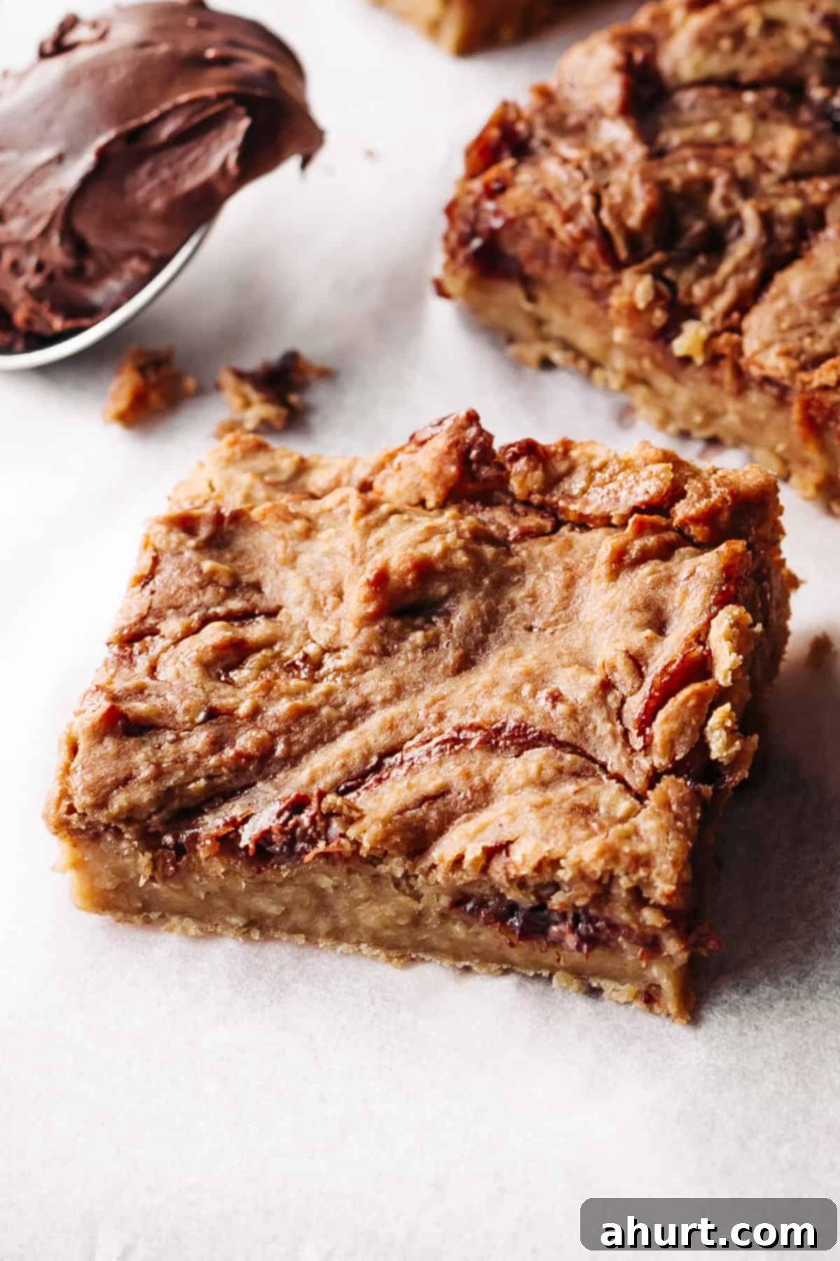 Jam and Nutella swirled blondie piece on parchment paper, showcasing its moist, fudgy texture