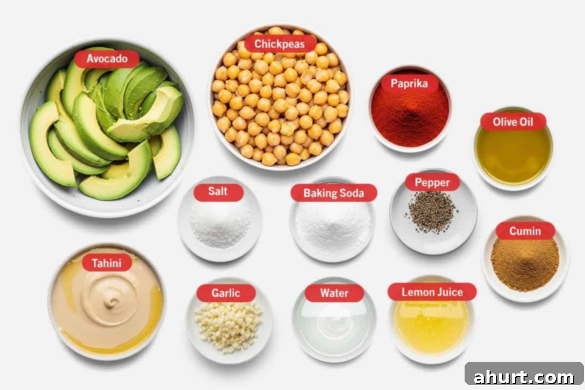 Creamy Avocado Hummus 3 Top-down view of avocado hummus ingredients: avocado, chickpeas, paprika, olive oil, salt, baking soda, pepper, cumin, tahini, garlic, water, and lemon juice.