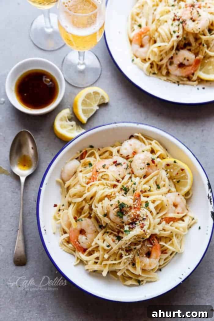 Nutty Browned Butter Shrimp Scampi 2 Browned Butter Shrimp Scampi with Parmesan Pasta! on a plate with spoon, black sauce and some lemon wedges kept aside on the table