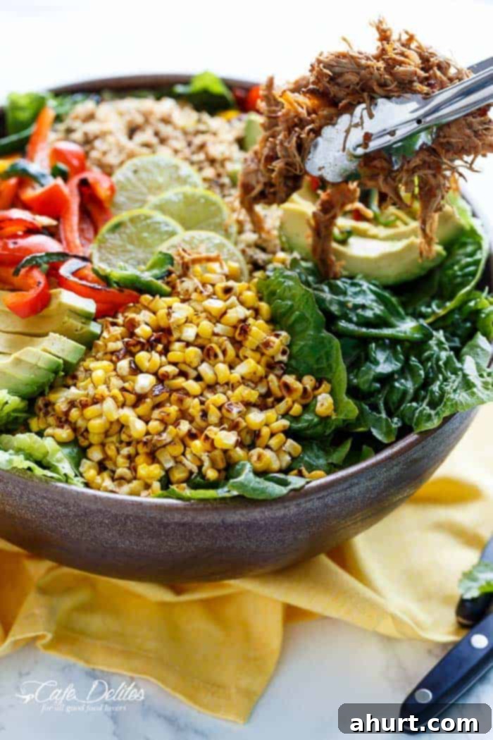 Side view of a generous bowl of Chipotle Lime Carnitas Salad, showcasing layers of crispy pork, fresh vegetables, and rice.