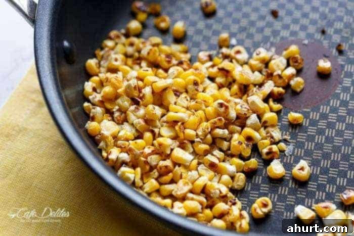 Process of shallow frying fresh corn kernels in a pan, toasting them to perfection for the salad.