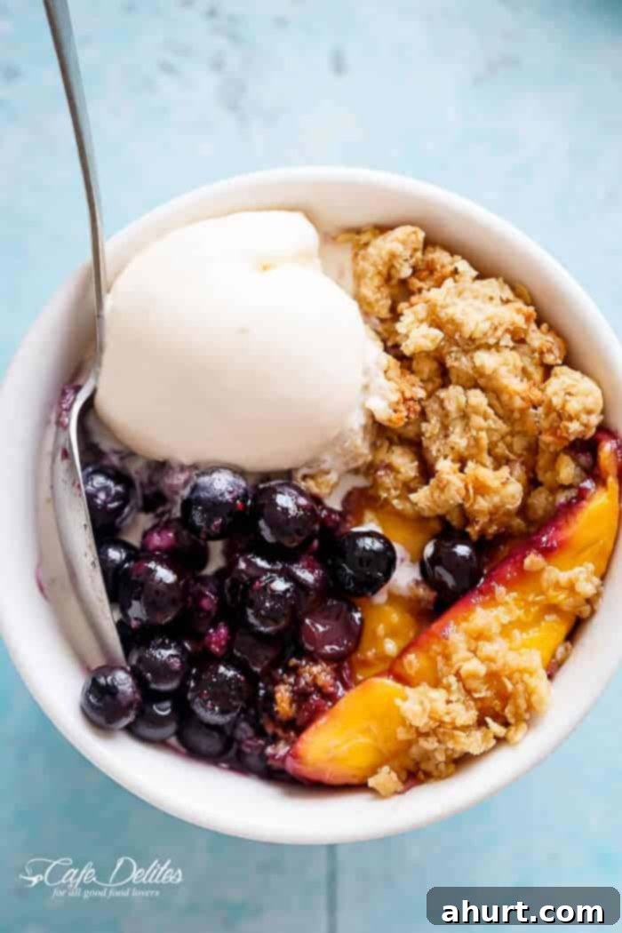 Mango Blueberry Crumble with fresh berries and ice cream scoops in a bowl