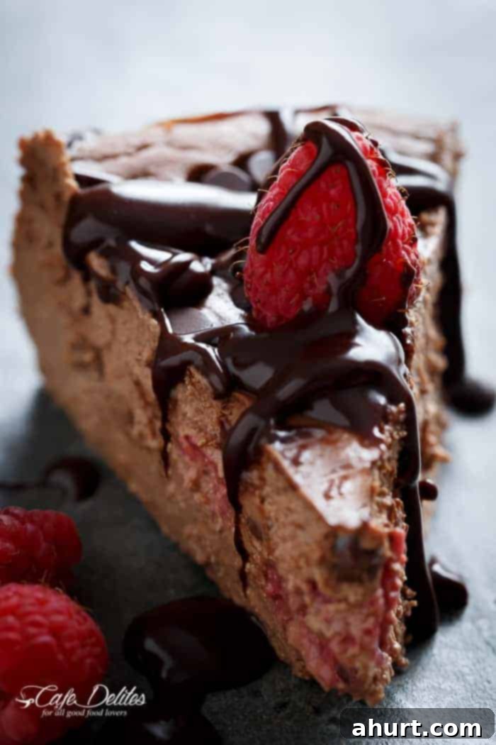 A slice removed from a whole Crustless Chocolate Raspberry Cheesecake, showing the creamy texture and raspberries