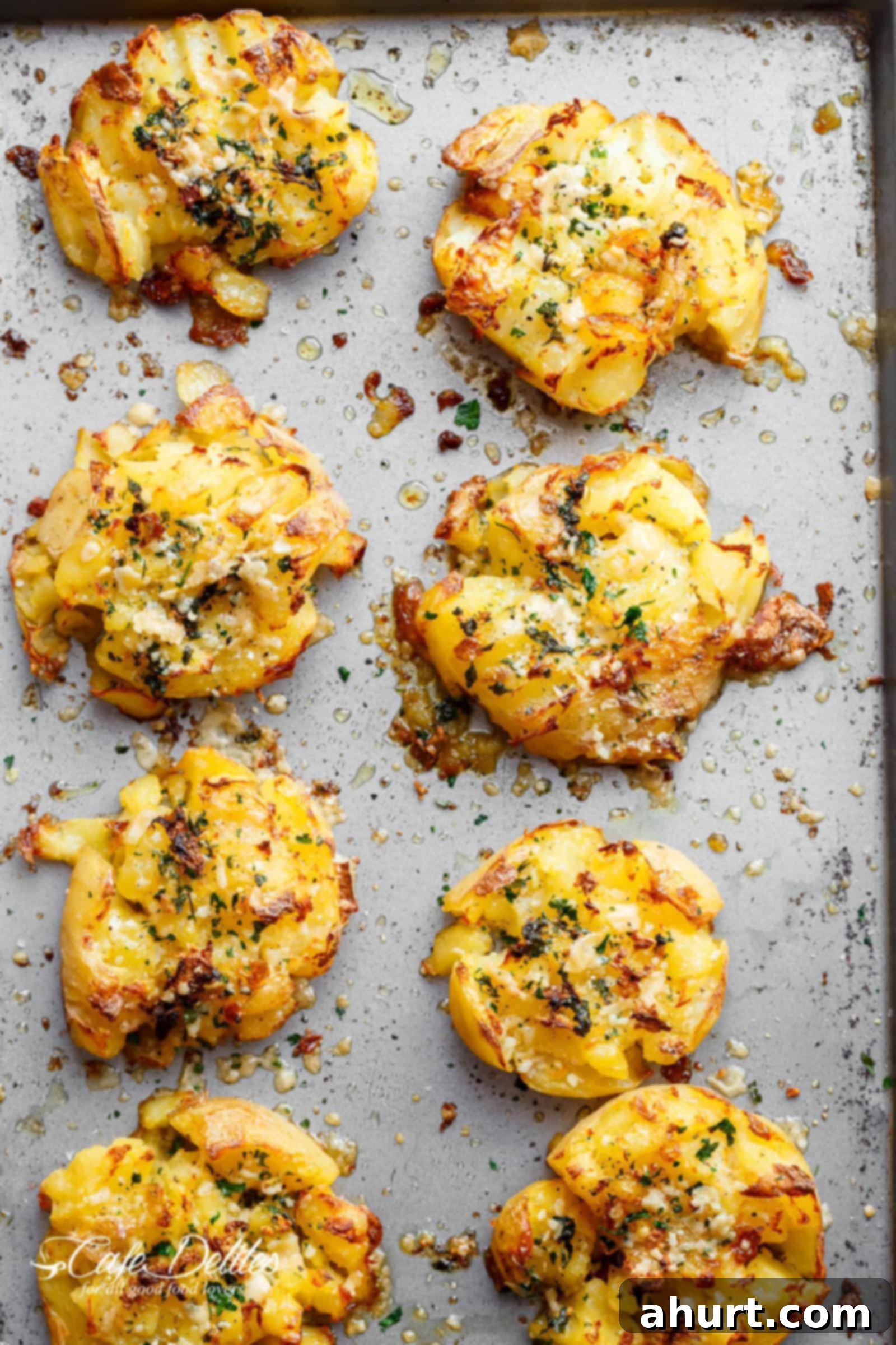 Ultimate Crispy Garlic Butter Parmesan Smashed Potatoes 2 Golden brown crispy garlic butter parmesan smashed potatoes, fluffy on the inside and crunchy on the outside, served on a baking sheet.