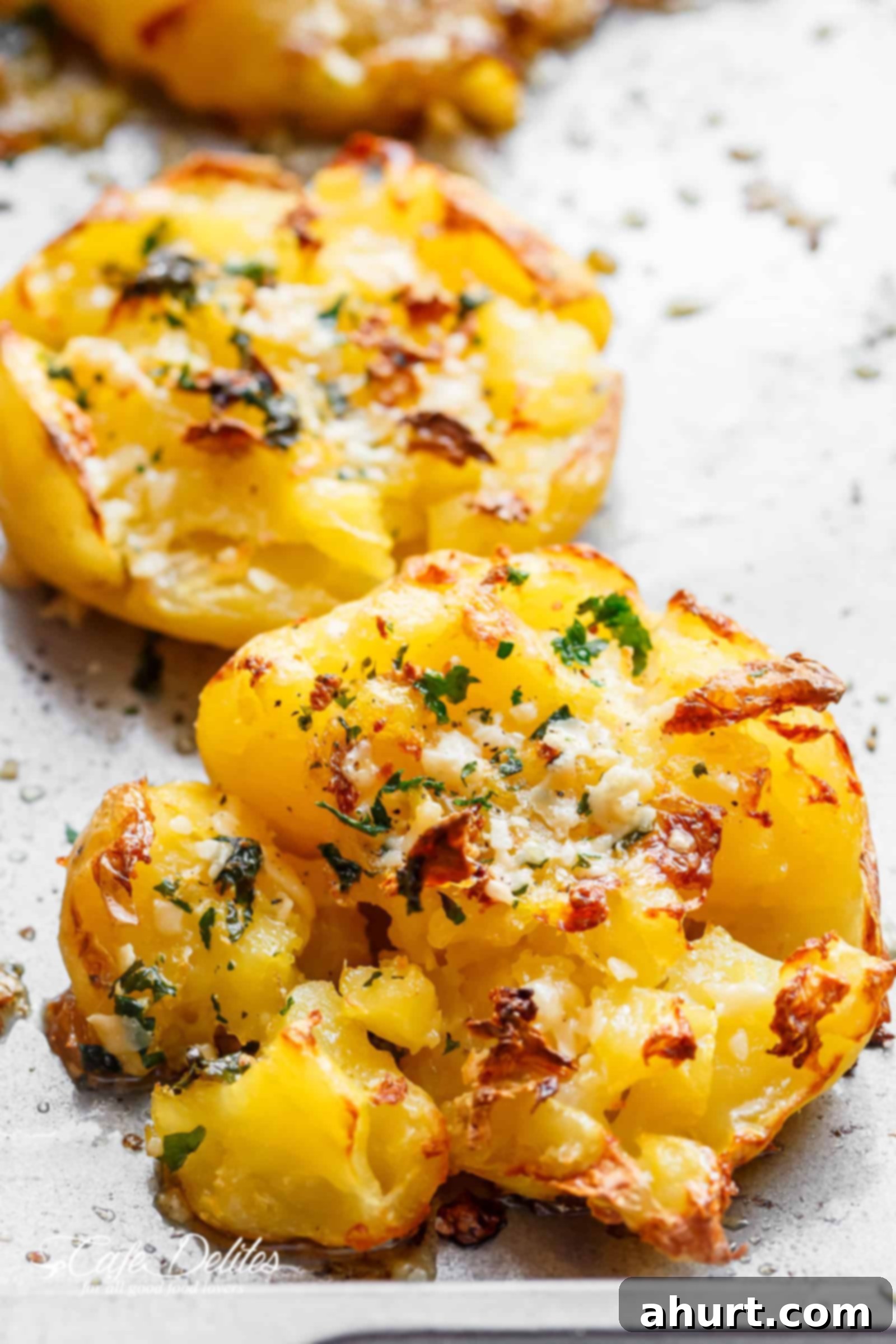 Ultimate Crispy Garlic Butter Parmesan Smashed Potatoes 5 Two pieces of Crispy Garlic Butter Parmesan Smashed Potatoes, perfectly golden and garnished with fresh parsley.