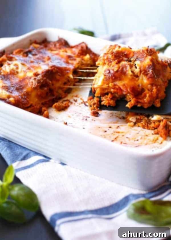 Harvest Chicken Pumpkin Ricotta Lasagna 2 A piece being taken from a freshly baked Chicken Pumpkin and Ricotta Lasagna, showing melted cheese and layers.