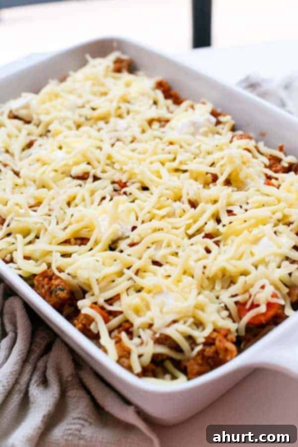 Harvest Chicken Pumpkin Ricotta Lasagna 4 Shredded cheese generously sprinkled over Chicken Pumpkin and Ricotta Lasagna, ready for baking.