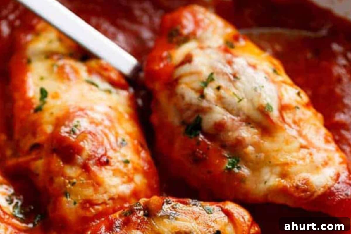 Chicken Mozzarella 9 A close-up of a perfectly cooked Mozzarella Chicken fillet, glistening with melted cheese and rich tomato sauce, garnished with fresh herbs, ready to be served.