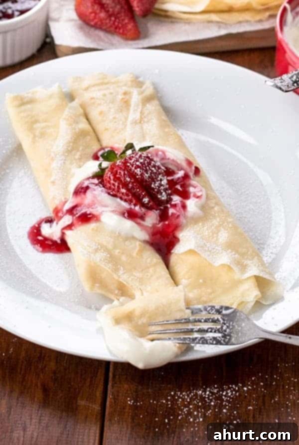 Strawberry Cheesecake Crepes with ice cream scoop on a plate