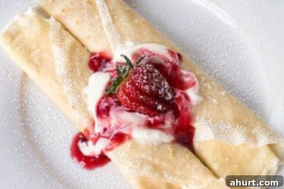 Spoon about 2 tablespoon of cheesecake filling down the center of the crepe. Add strawberries on top.