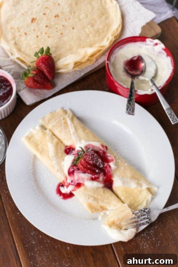 Top view image of Strawberry Cheesecake Crepes with white cream in the bowl and some fresh strawberries