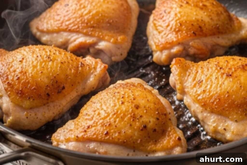 Chicken thighs searing skin-side down in an oven-proof skillet until golden.