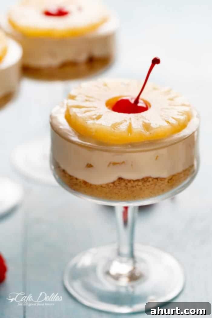 Refreshing No-Bake Pineapple Cheesecake in a glass jar, garnished with a pineapple ring and maraschino cherry