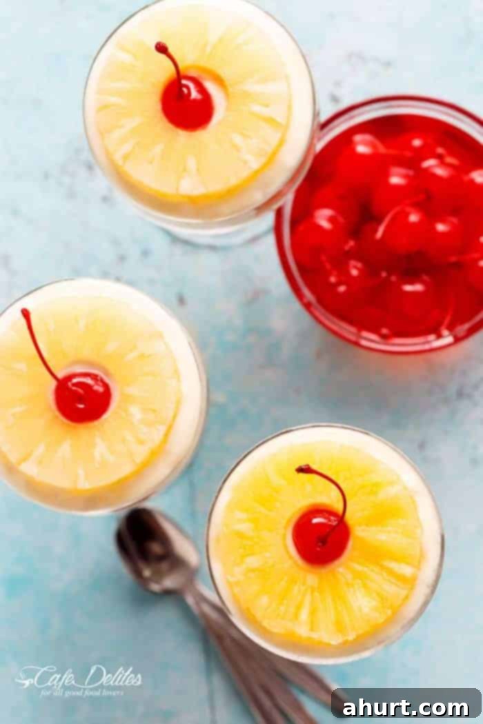 Top view of four individual No-Bake Pineapple Cheesecakes in glasses, with pineapple rings and cherries