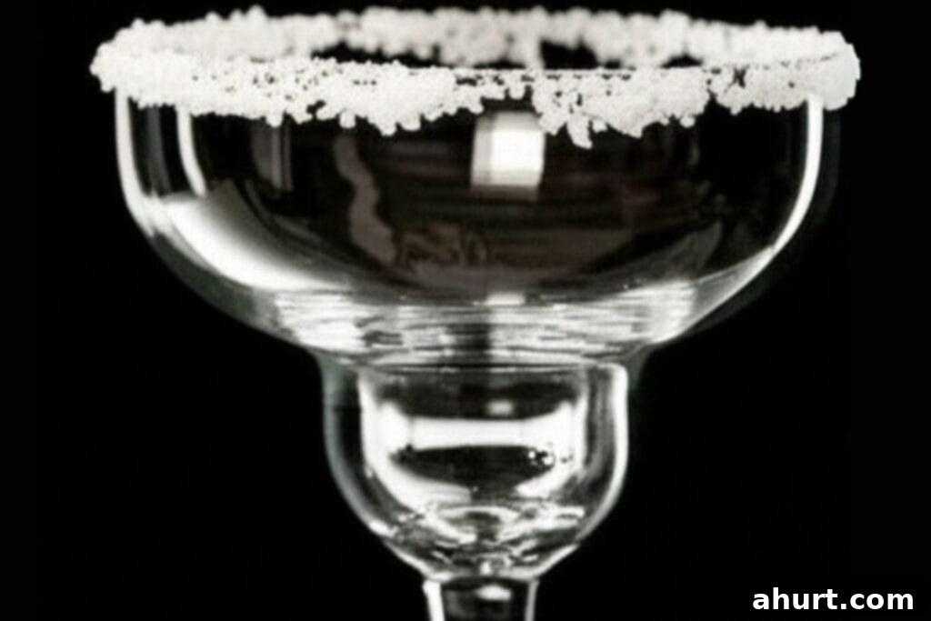 Blended Margarita Bliss 4 A close-up image showing a lime wedge being rubbed around the rim of a cocktail glass to prepare for salting.