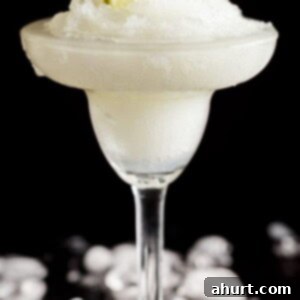 Blended Margarita Bliss 7 Side view image of Frozen Margarita Slushy, a vibrant green drink in a salt-rimmed glass.