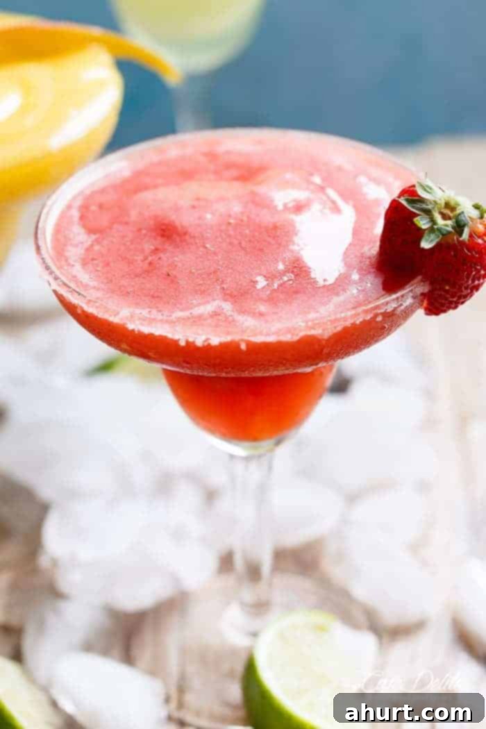 Tropical Strawberry Mango Margaritas 4 A close-up of a vibrant Frozen Strawberry Margarita in a glass, demonstrating its smooth, icy texture and festive appeal.