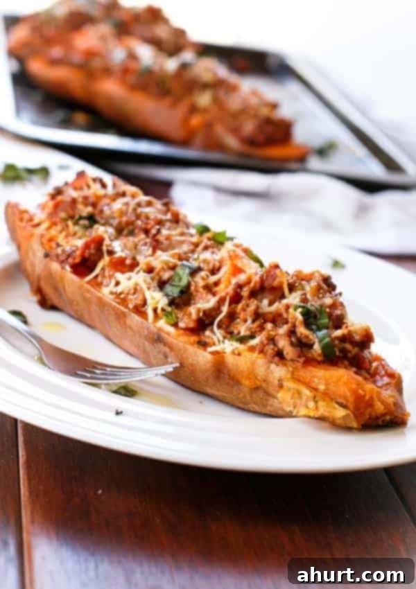 Sweet Potato Boats with Cheesy Bacon Bolognese 2 Bacon Bolognese Stuffed Sweet Potatoes with fork on a plate