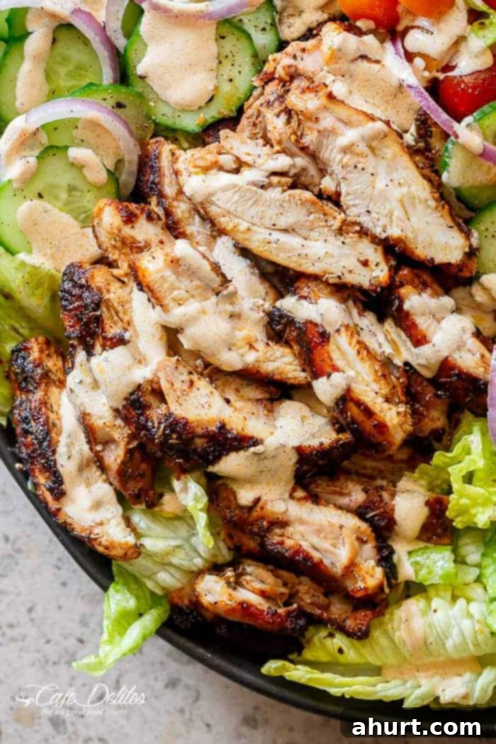 Close-up of juicy grilled Cajun chicken pieces in a vibrant salad with creamy dressing