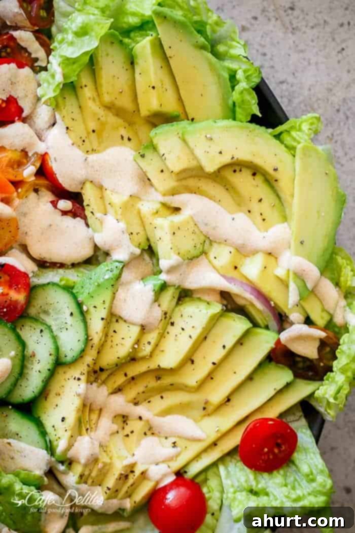Close-up of fresh avocado slices and vibrant vegetables in a Grilled Cajun Chicken Salad