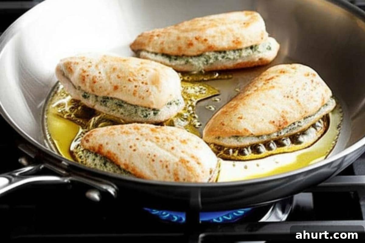 Cheesy Spinach Artichoke Stuffed Chicken 8 Stuffed chicken breasts sizzling and searing to a golden brown in a large skillet on the stovetop.