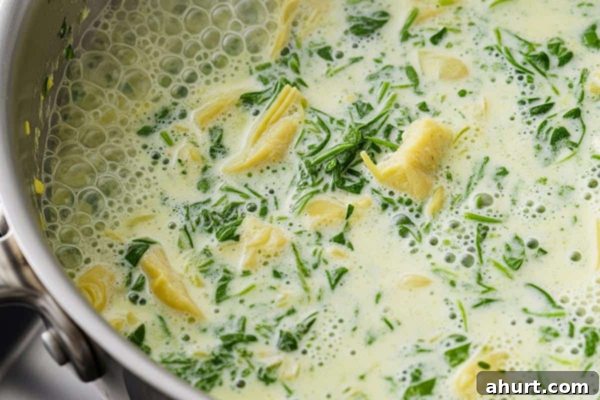 Cheesy Spinach Artichoke Stuffed Chicken 10 Half and half being poured into a skillet with the remaining spinach artichoke dip, stirring to create a creamy sauce.