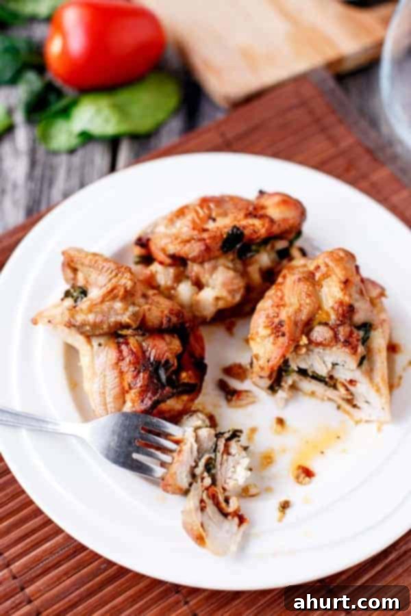 Feta Bacon Sundried Tomato Chicken Roulades 9 Fork pierced into a piece from Fetta and Sundried Tomato Stuffed Chicken and Spinach Rolls