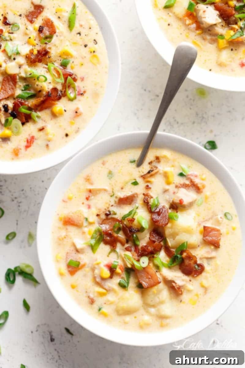 Three bowls of creamy chicken corn chowder, garnished with crispy bacon and fresh chopped spring onions, ready to be enjoyed.