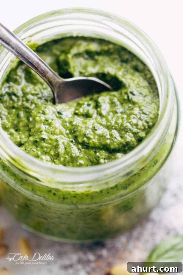 Freshly Made Basil Pesto Perfection 2 A vibrant green bowl of freshly homemade basil pesto with a spoon, perfect for pasta or grilled dishes. Much better than any store-bought alternative, requiring only 5 ingredients and a food processor.